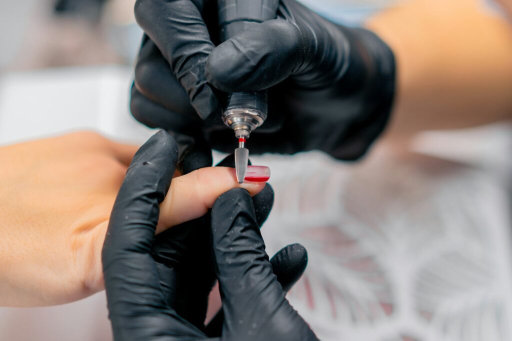 close-up a manicurist removes nail polish from a client's nails with a nail polish remover in salon